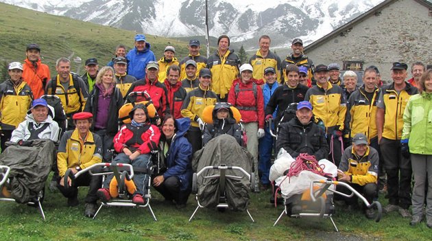 Eine Wandergruppe mit Trekking-Rollstühlen in den Bergen.