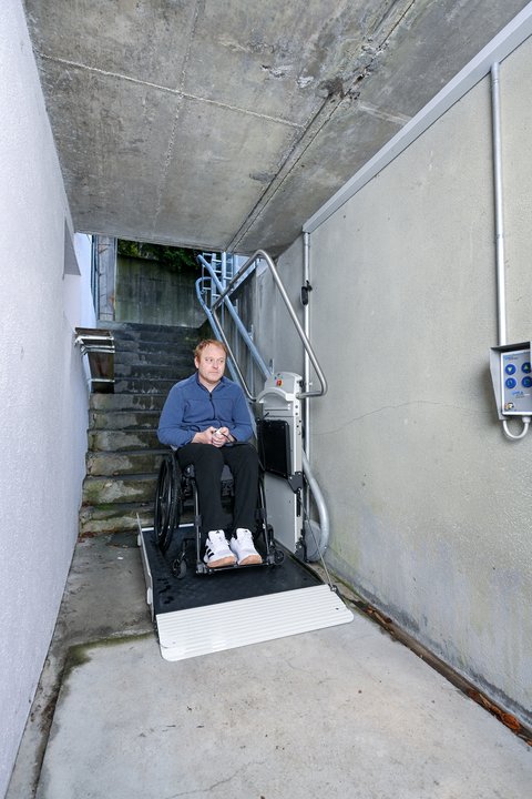 Un utilisateur de fauteuil roulant descend à la cave sur un monte-escalier