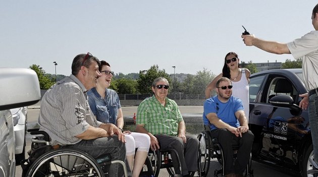 Eine Gruppe Rollstuhlfahrer wird von einem Instruktor ins Autofahren eingeführt 