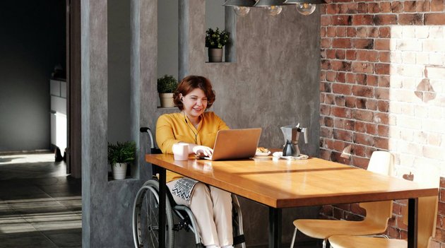 Eine junge Frau sitzt im Wohnzimmer und arbeitet am Computer