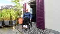 Ein Mann im Rollstuhl fährt über eine Rampe in den Garten