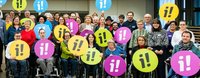Menschen mit und ohne Behinderungen, die das Logo der Inklusionsinitiative in die Luft halten