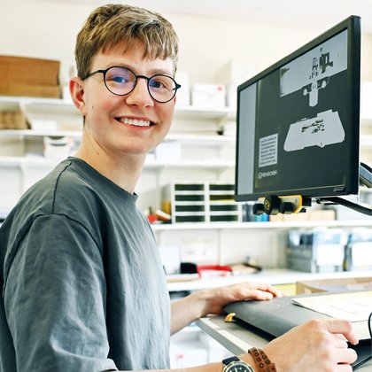 Jonas Vögeli schaut vor seinem speziellen Bildschirm lachend in die Kamera
