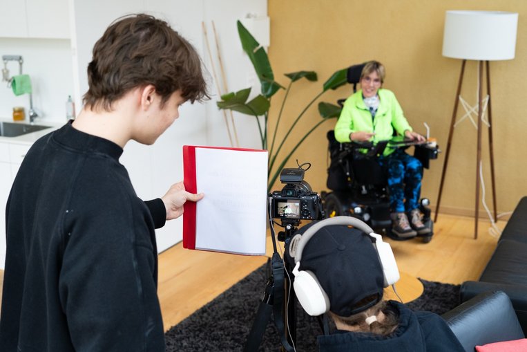 Ein Blick hinter die Kulissen: Es zeigt den Videodreh vor Ort mit dem Kamerateam und einer Protagonistin im Rollstuhl.