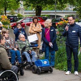 Rollstuhlfahrer und andere Menschen hören einem Mann gespannt zu