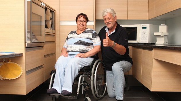 Eine Frau im Rollstuhl mit einem Bauberater in einer angepassten Küche.