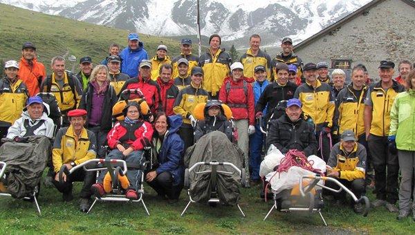 Eine Wandergruppe mit Trekking-Rollstühlen in den Bergen.