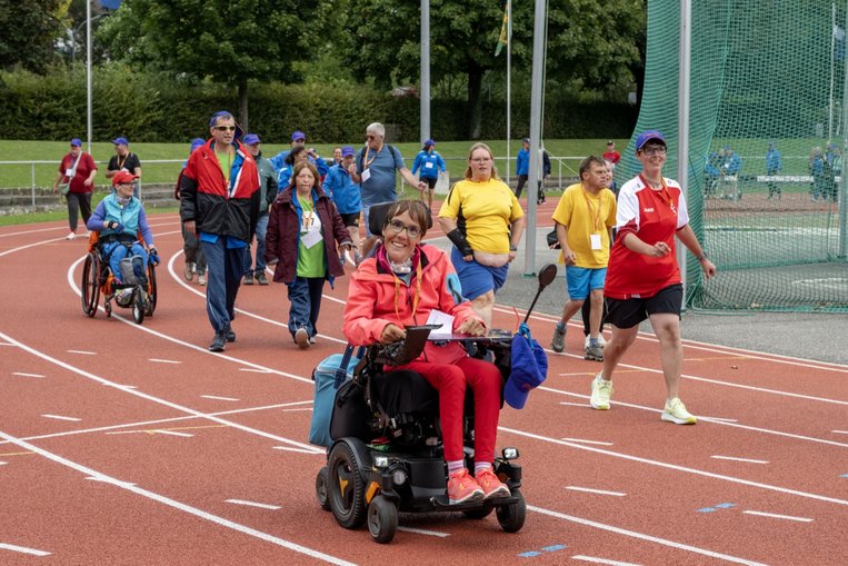 Menschen mit und ohne Rollstuhl beim Laufen auf der Tartanbahn