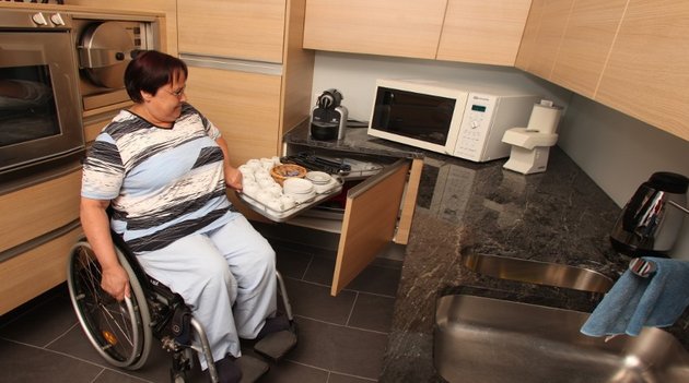 Une femme en fauteuil roulant dans sa cuisine adaptée.