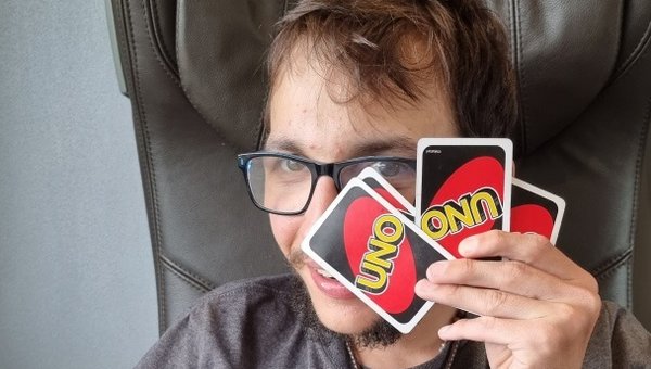 Sebastian hält Uno-Karten vor dem Kopf und schaut verschmitzt durch eine Lücke im Kartenblatt