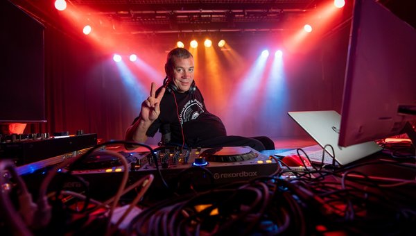 DJ Threnie alias René Sittig sitzt hinter dem Mischpult und macht das Victory-Zeichen