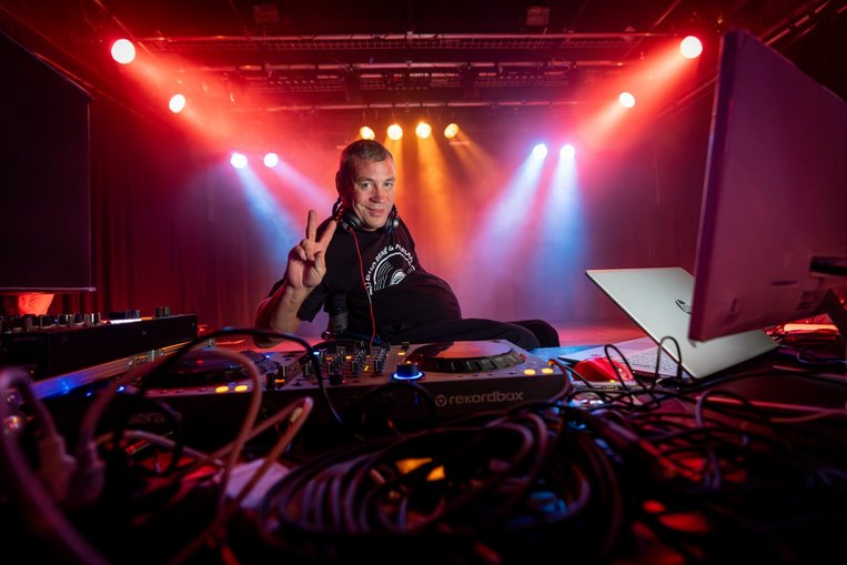 DJ Threnie alias René Sittig sitzt hinter dem Mischpult und macht das Victory-Zeichen