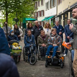 Rollstuhlfahrer und andere Menschen hören einem Mann aufmerksam zu