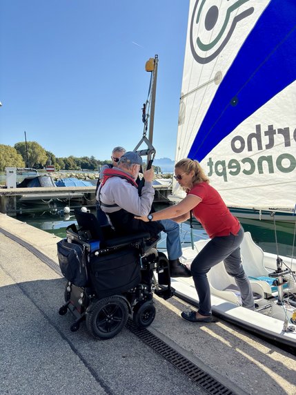 Un participant en fauteuil roulant électrique est embarqué sur un voilier.
