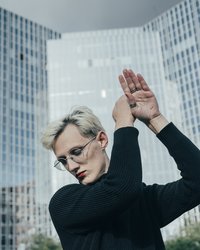 Performer vor Hochhäusern deren Fassaden grösstenteils aus Glas sind.