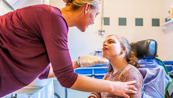 Une mère s'occupe de sa fille en fauteuil roulant.