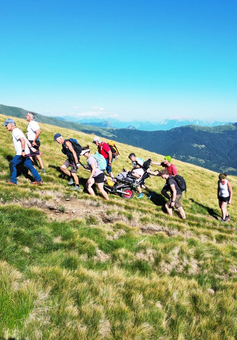Un groupe de randonneurs équipés de fauteuils roulants de randonnée sur un terrain montagneux escarpé