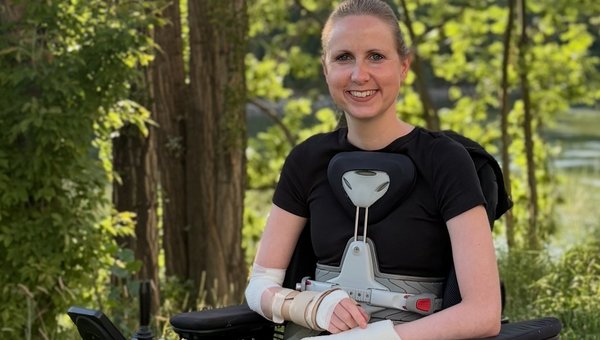 Céline est assise dans un fauteuil roulant électrique lors d'une promenade en forêt