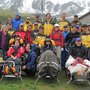 Eine grosse Wandergruppe mit 4 Personen im Trecking-Rollstuhl in den Bergen.