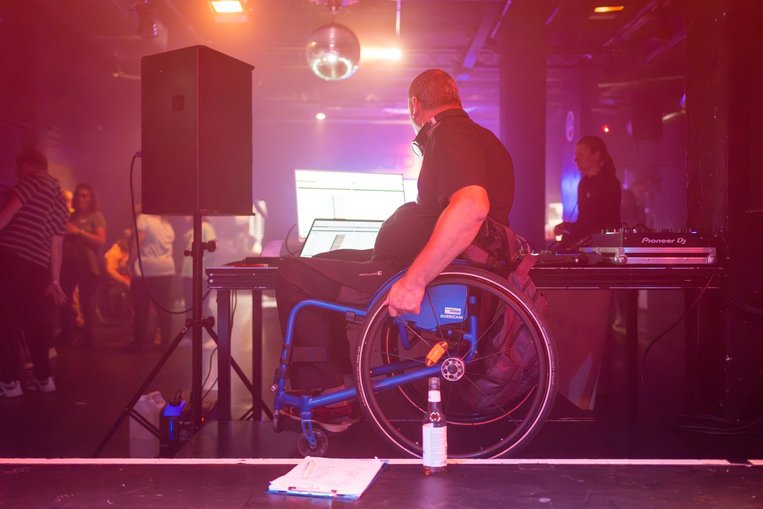 Ein Rollstuhlfahrer bedient das DJ-Pult