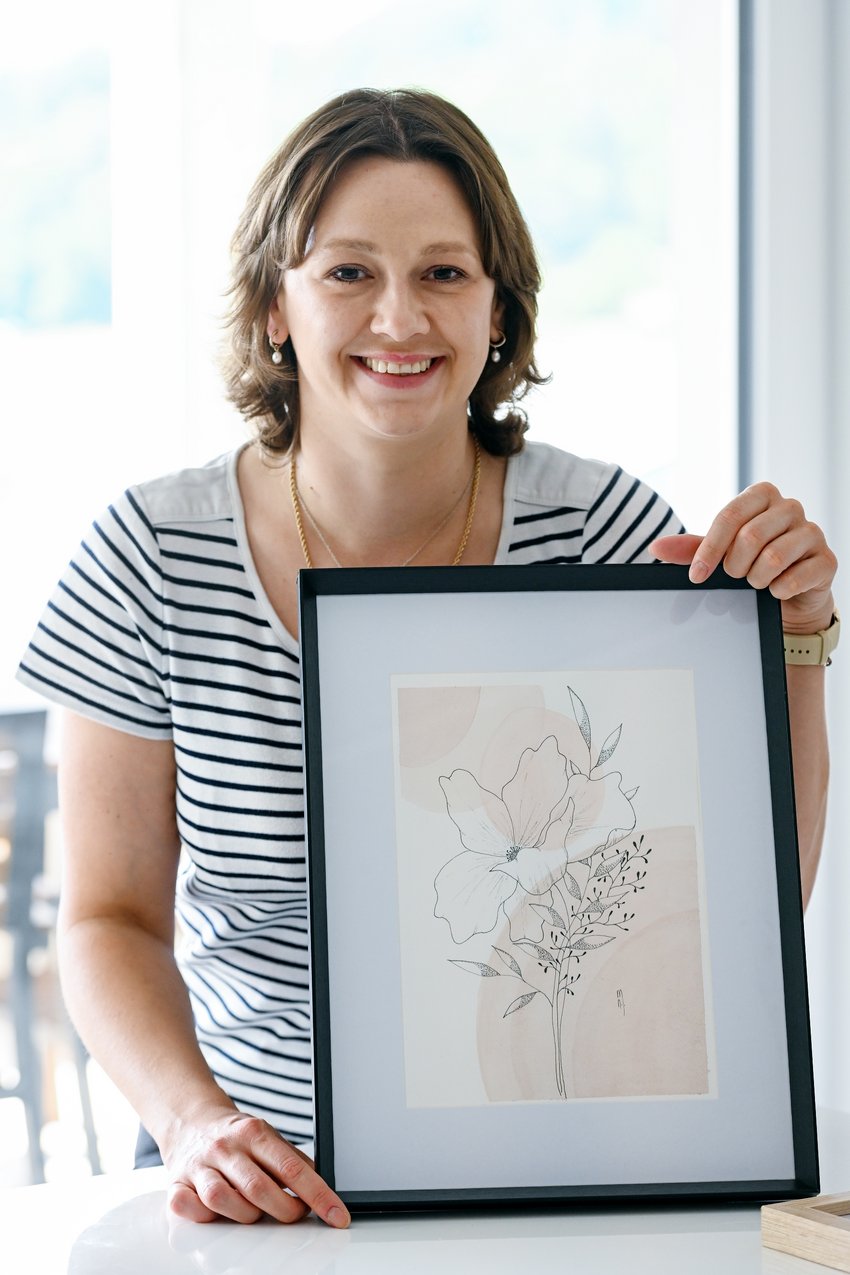 Natasa Milenkovic nous montrant, souriante, un tableau de fleurs qu'elle a peint