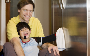 Un garçon handicapé s'est assis avec son père sur une chaise.