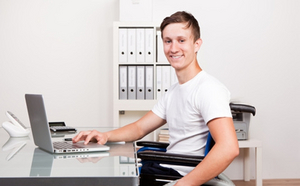 Un jeune homme s'est assis devant un laptop en souriant.
